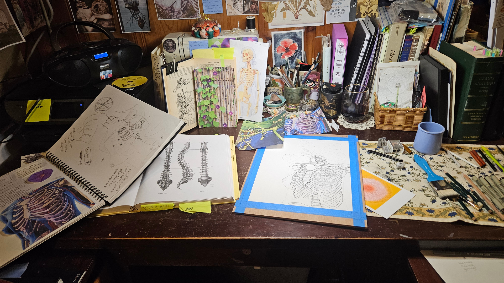 Kim Suter's studio desk with botanical drawings, art books, and supplies